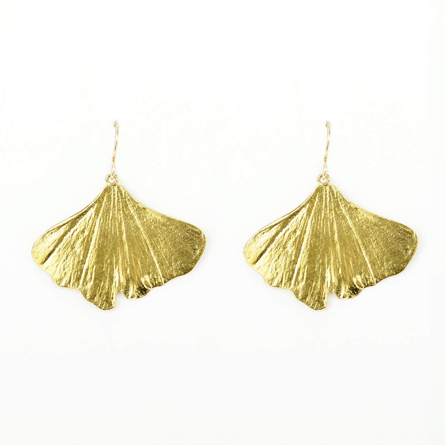 beautiful pair of golden ginkgo earrings on a white background