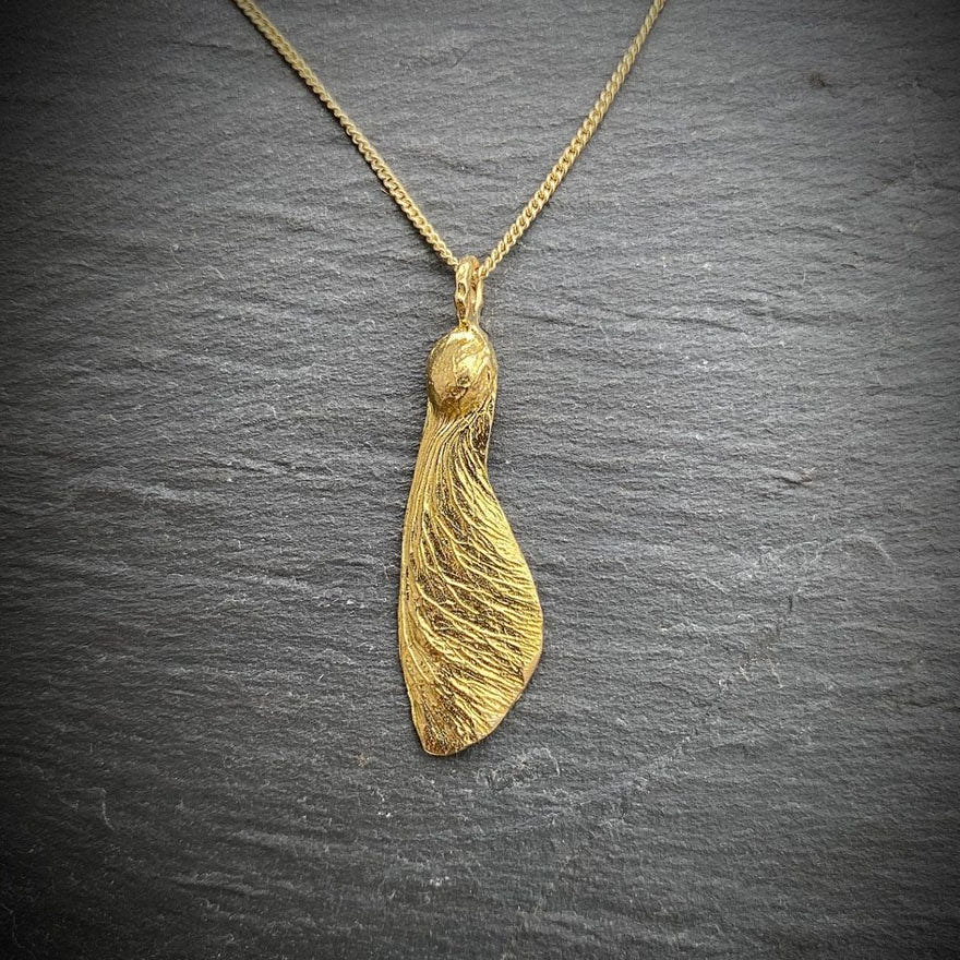 solo maple key necklace "helicopter" in golden on a slate background