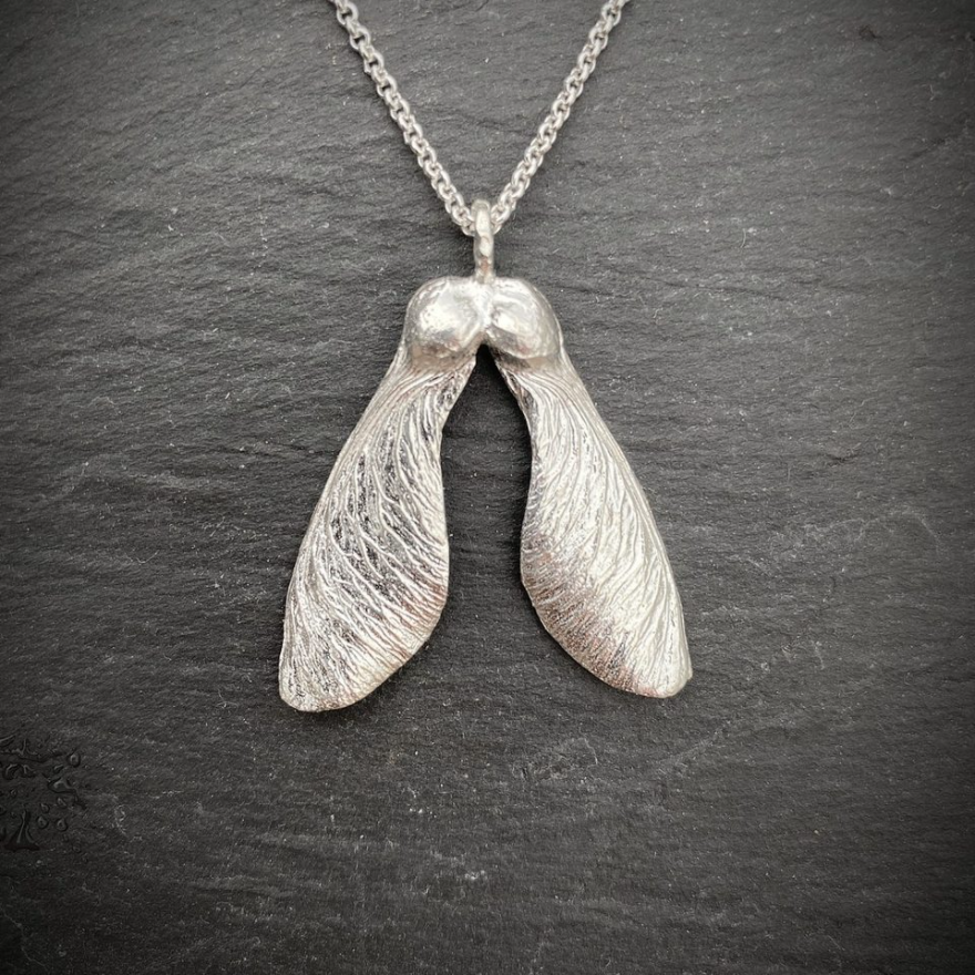 silver necklace with wonderful detail of a double maple key or "helicopter" on a slate tile background