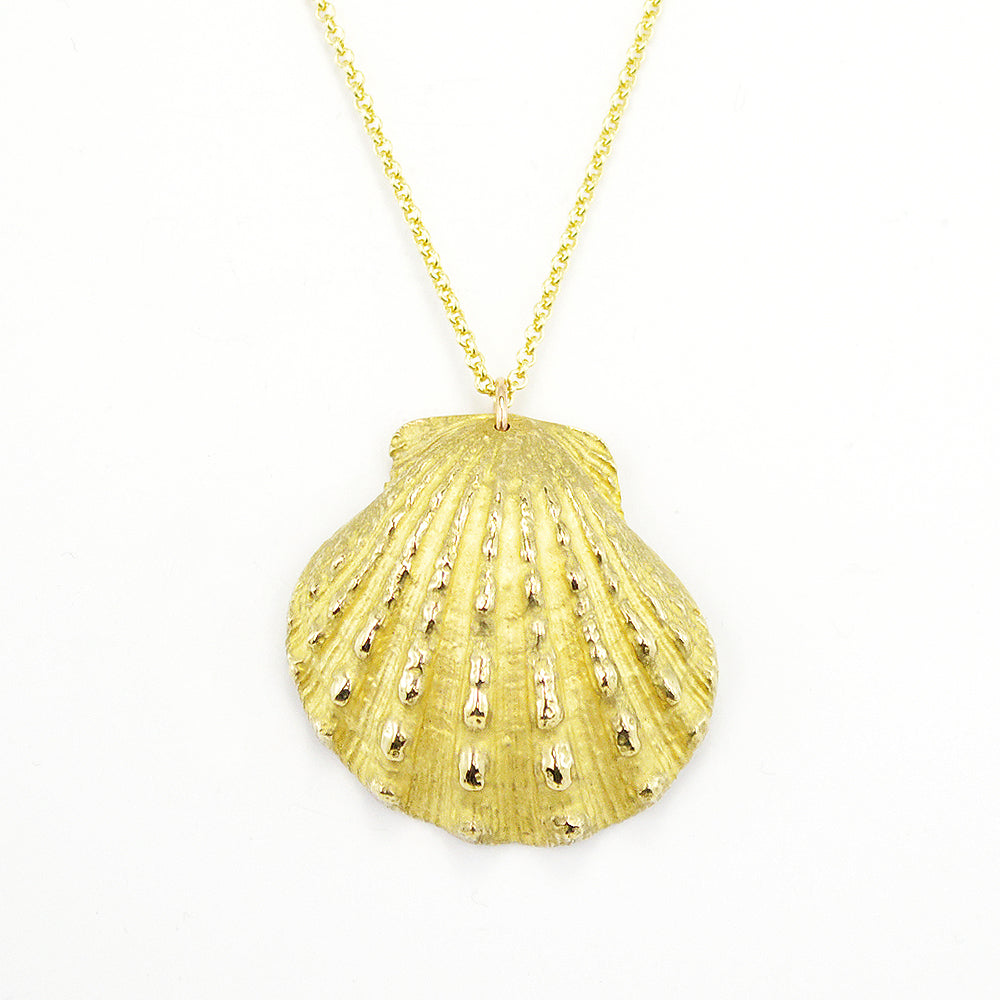 close up of beautiful, calming image of a scallop shell cast in a golden metal on a white background.