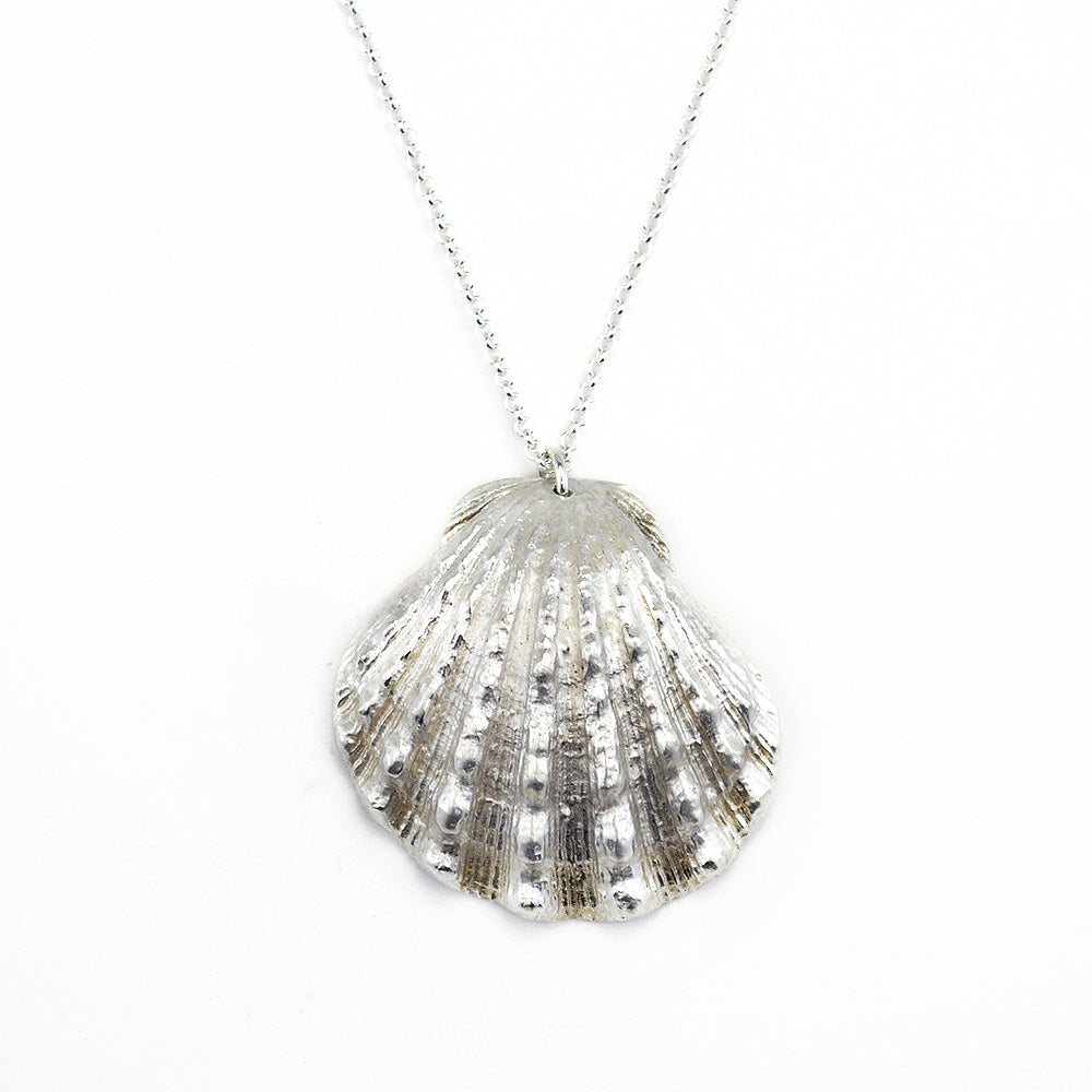 close up of beautiful, calming image of a scallop shell cast in sterling silver on a white background.