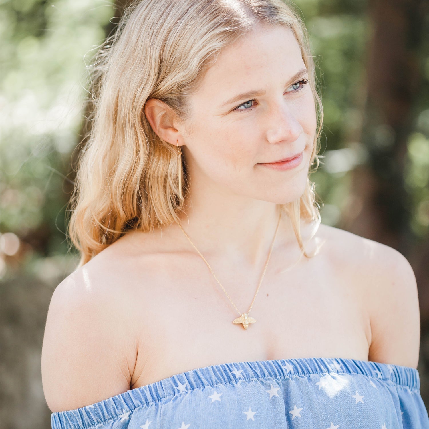 woman wearing gold bee necklace