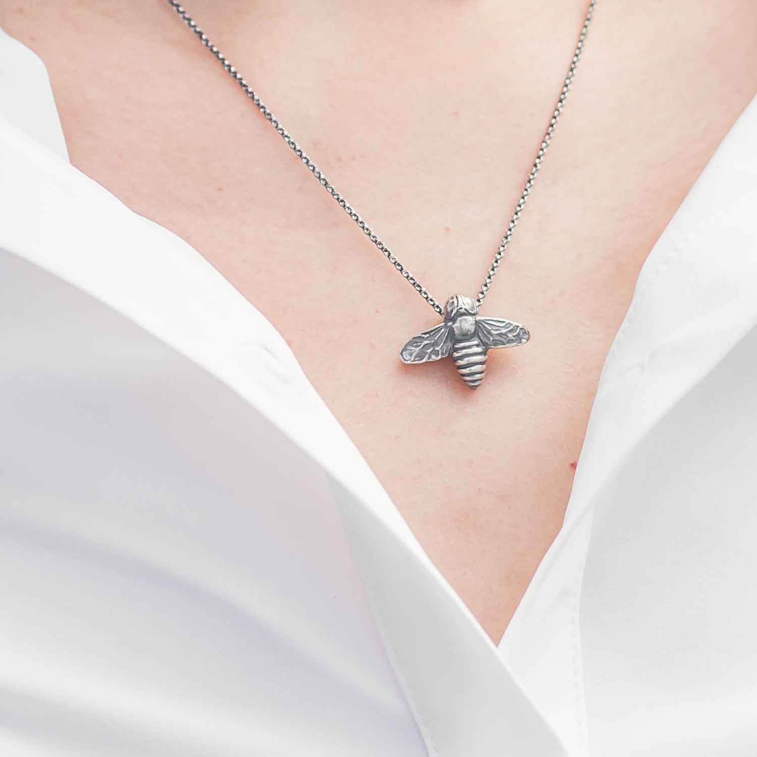 oxidized silver bee pendant worn with a white button down top