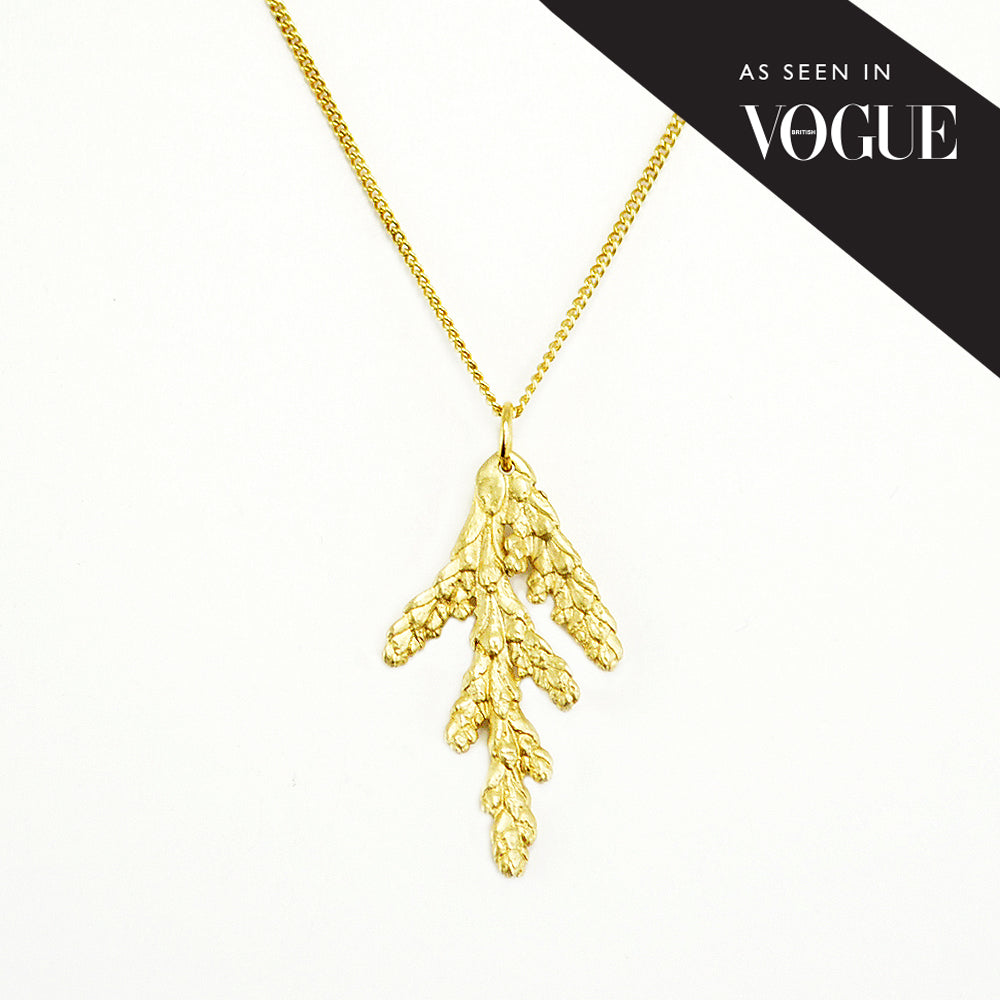 "As seen in Vogue" gold cedar necklace on white background