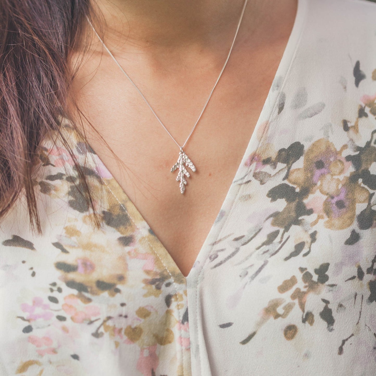 small silver cedar pendant worn with floral blouse