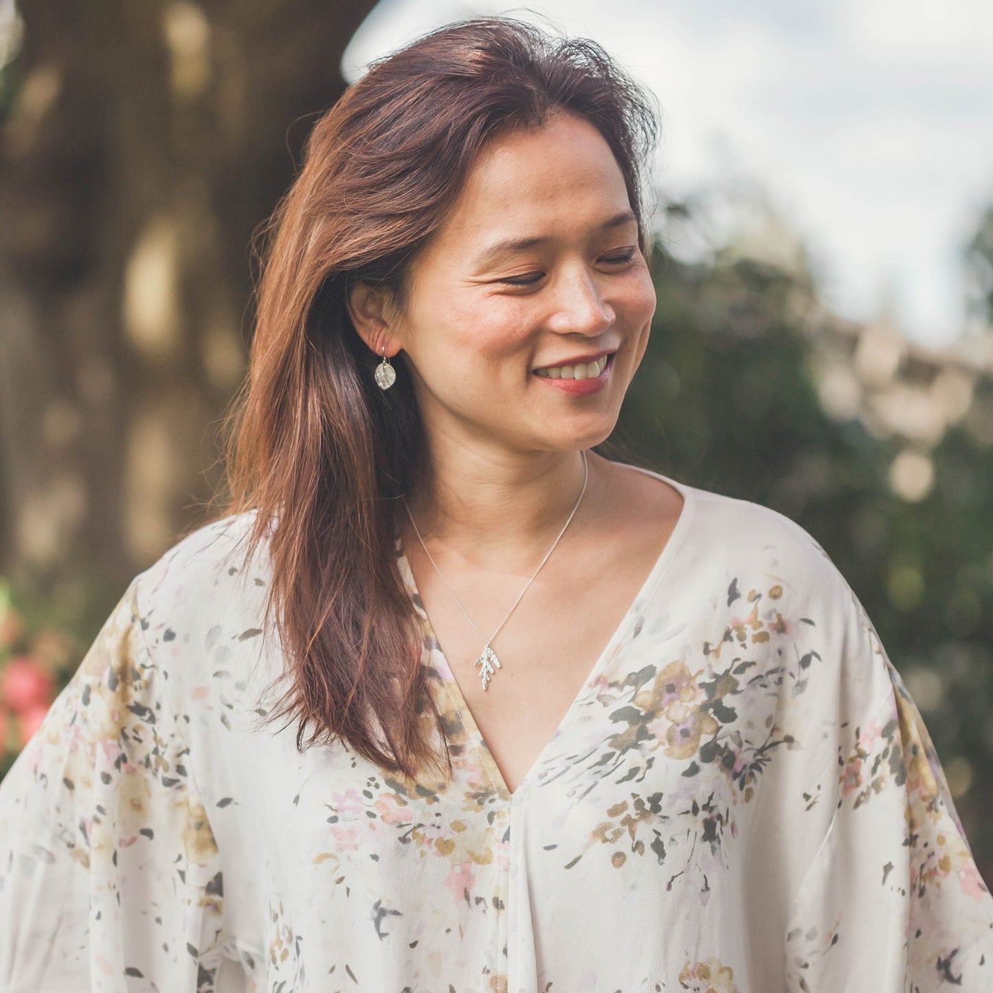 smiling woman wearing cedar necklace outside