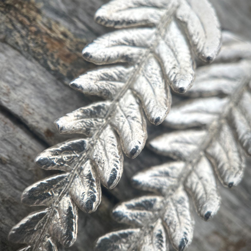 up close image of silver fern earring details