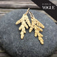 as seen in vogue. pair of golden cedar earrings atop a round stone