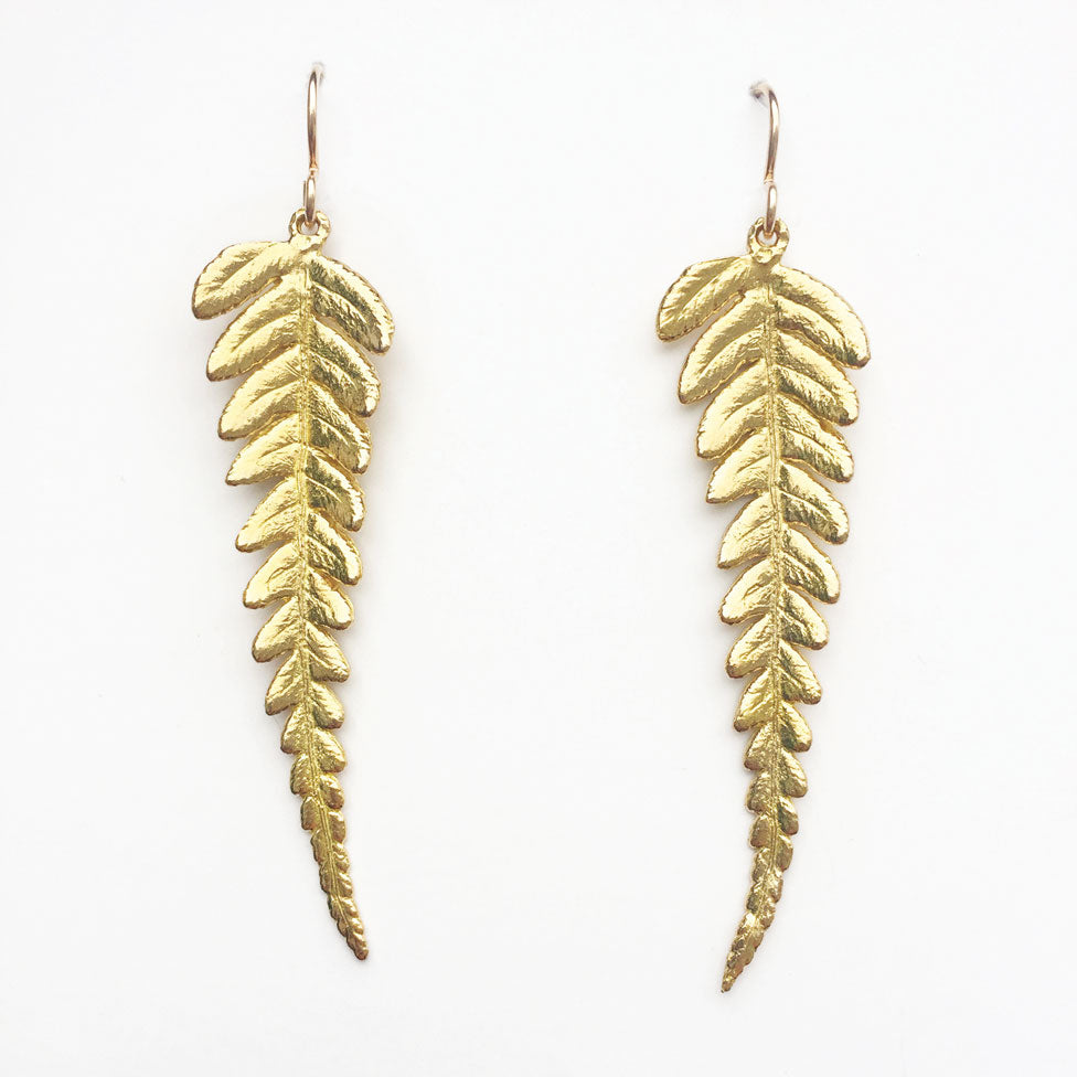 pair of golden fern earrings on white background