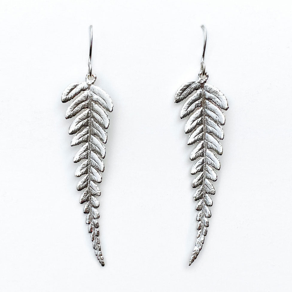 pair of silver fern earrings on white background