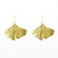 beautiful pair of golden ginkgo earrings on a white background 