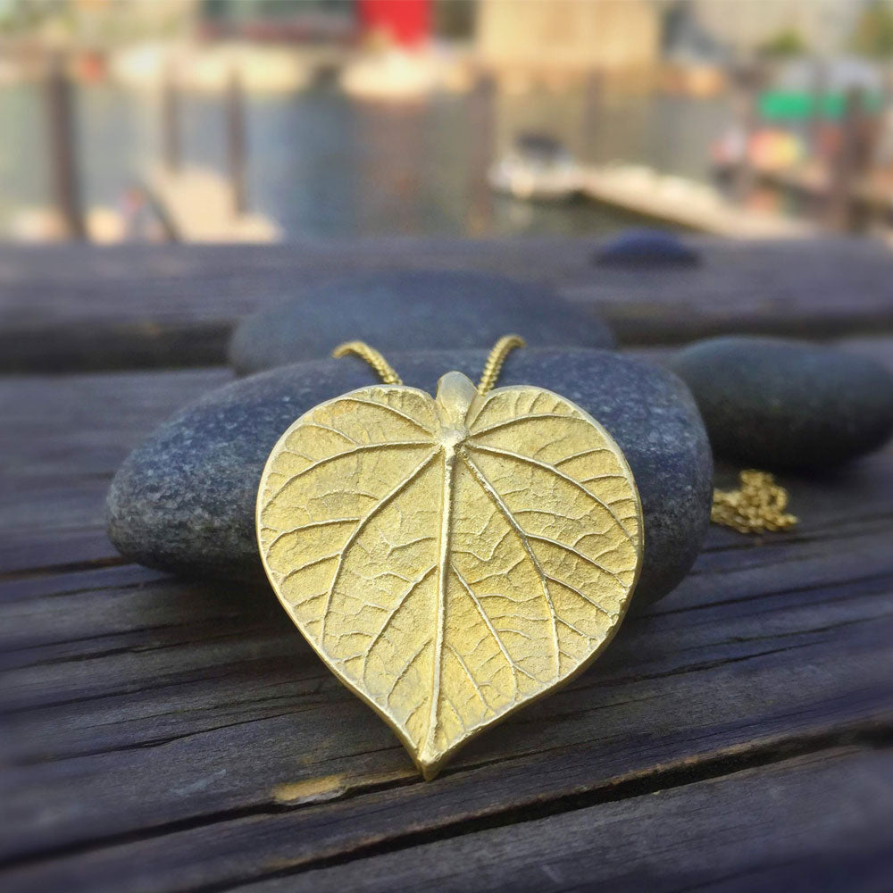 golden linden leaf draped over stone on wooden table outside