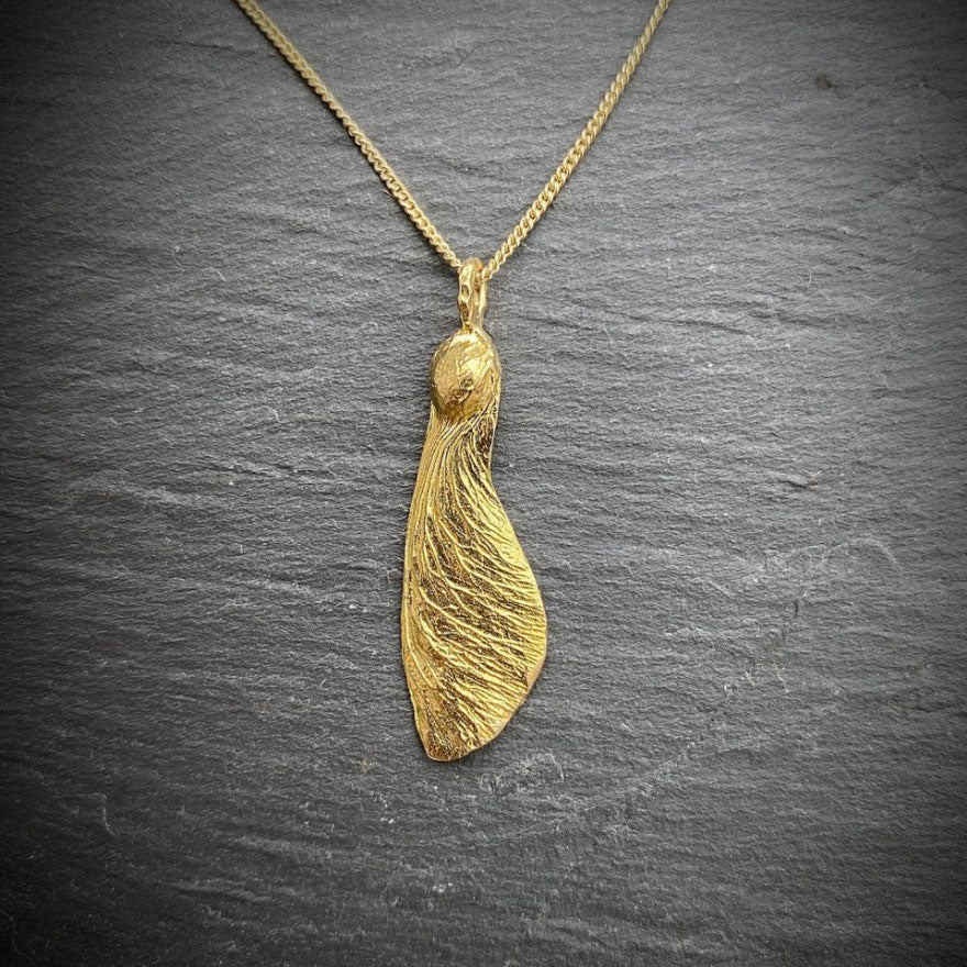 solo maple key necklace  "helicopter" in golden on a slate background