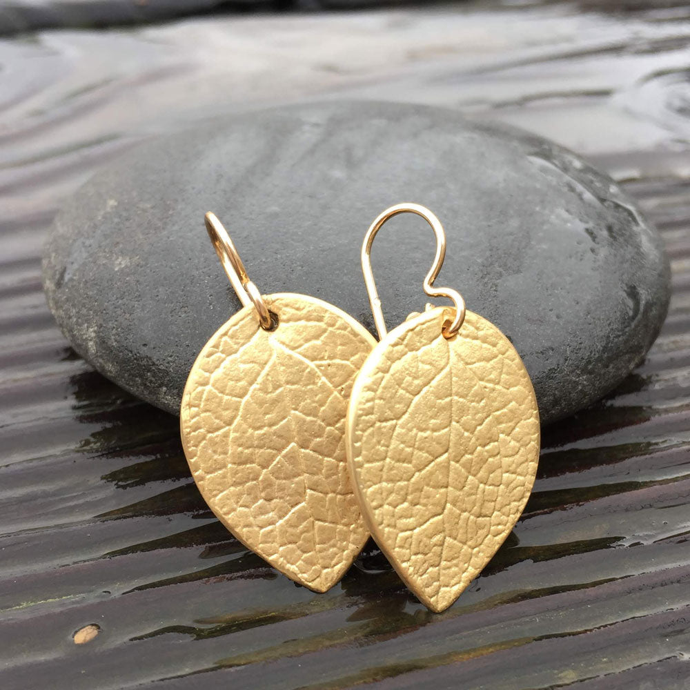 golden bronze salal leaf earrings perched agains rock 
