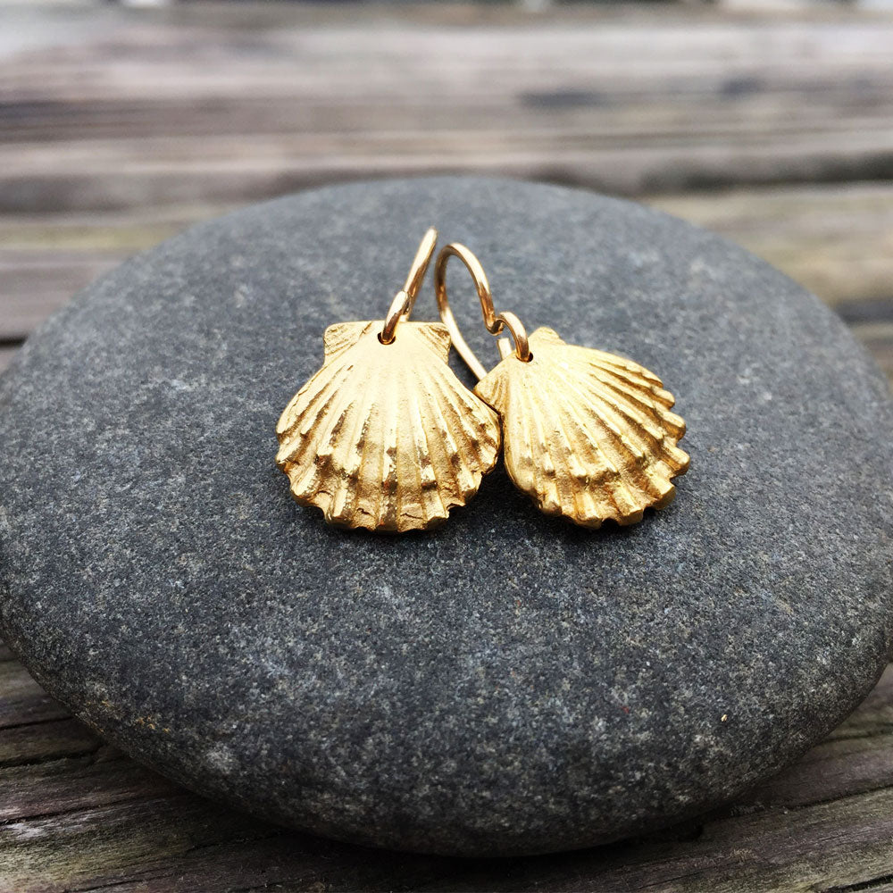golden bronze scallop shell earrings on top of a round stone 