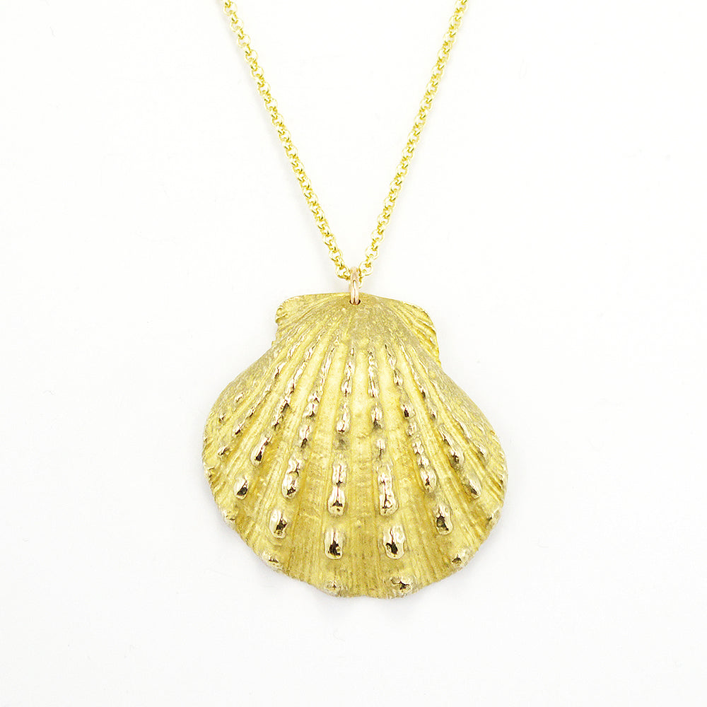 close up of beautiful, calming image of a scallop shell cast in a golden metal on a white background. 