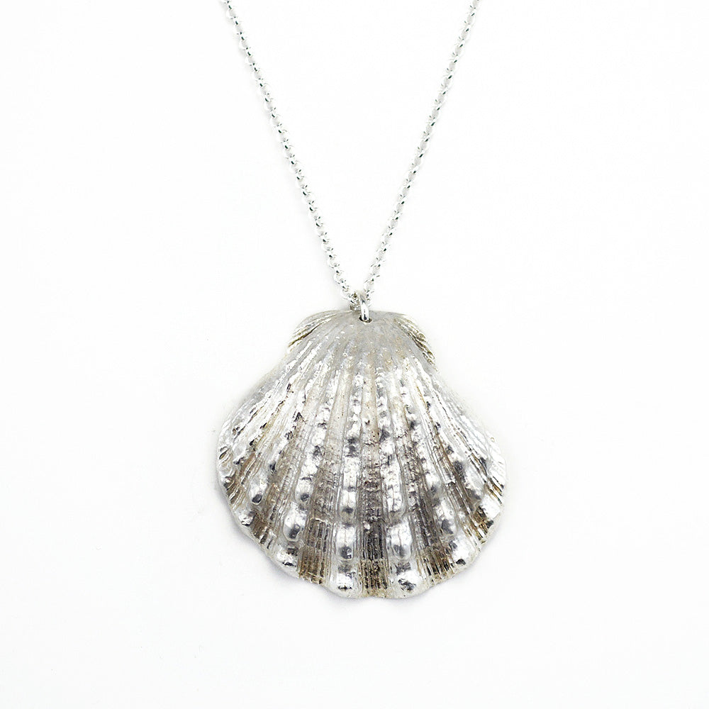 close up of beautiful, calming image of a scallop shell cast in sterling silver on a white background. 