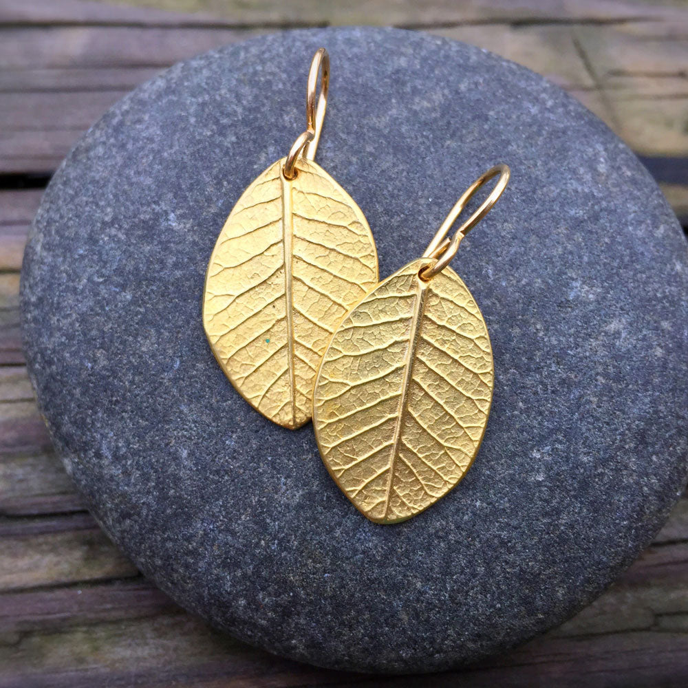 beautifully detailed golden bronze smokebush earrings on top of a round stone