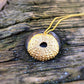 golden bronze sea urchin necklace on weathered rustic wooden surface with metal rivet