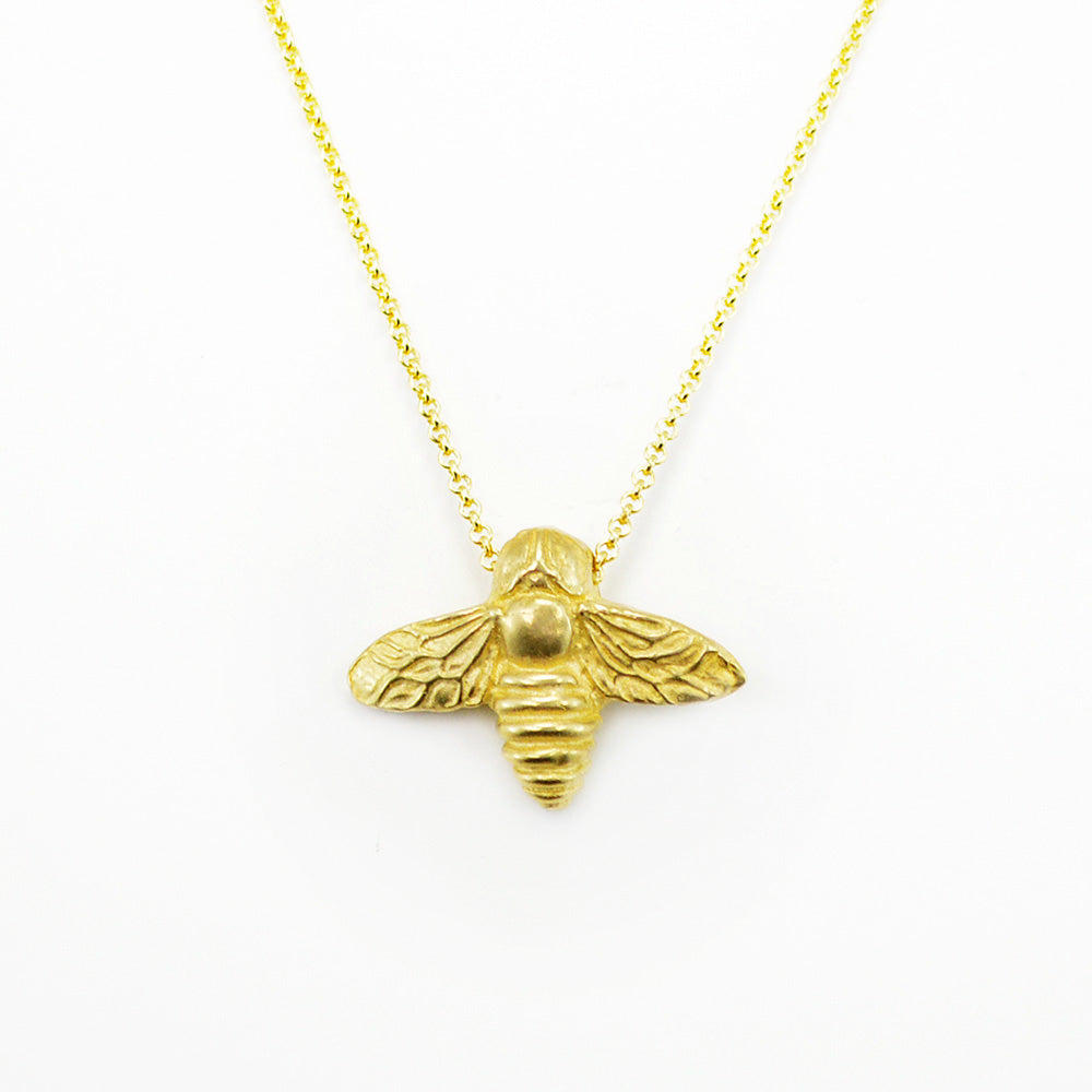 gold bee necklace on white background