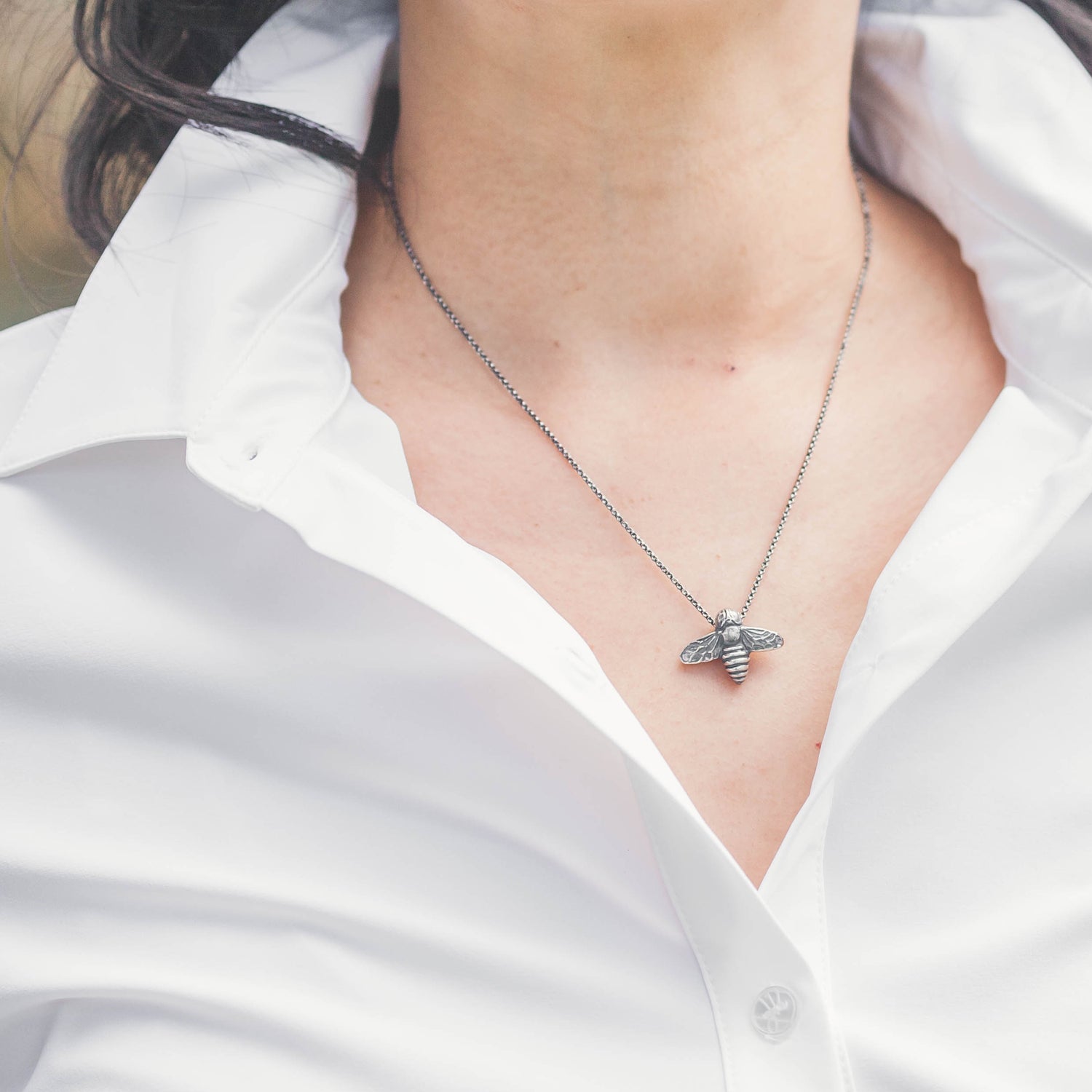 oxidized silver bee pendant worn with a white button down top