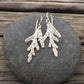 beautifully detailed silver cedar earrings on round gray stone