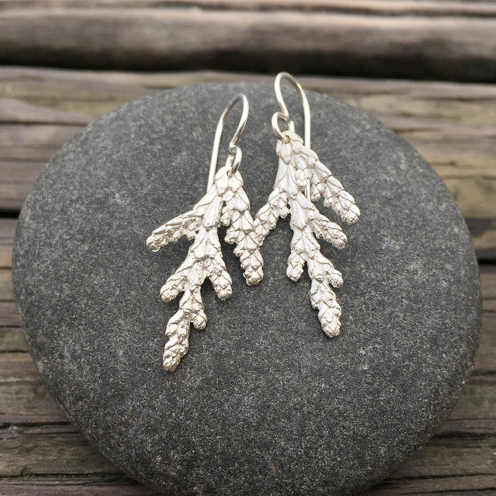 beautifully detailed silver cedar earrings on round gray stone