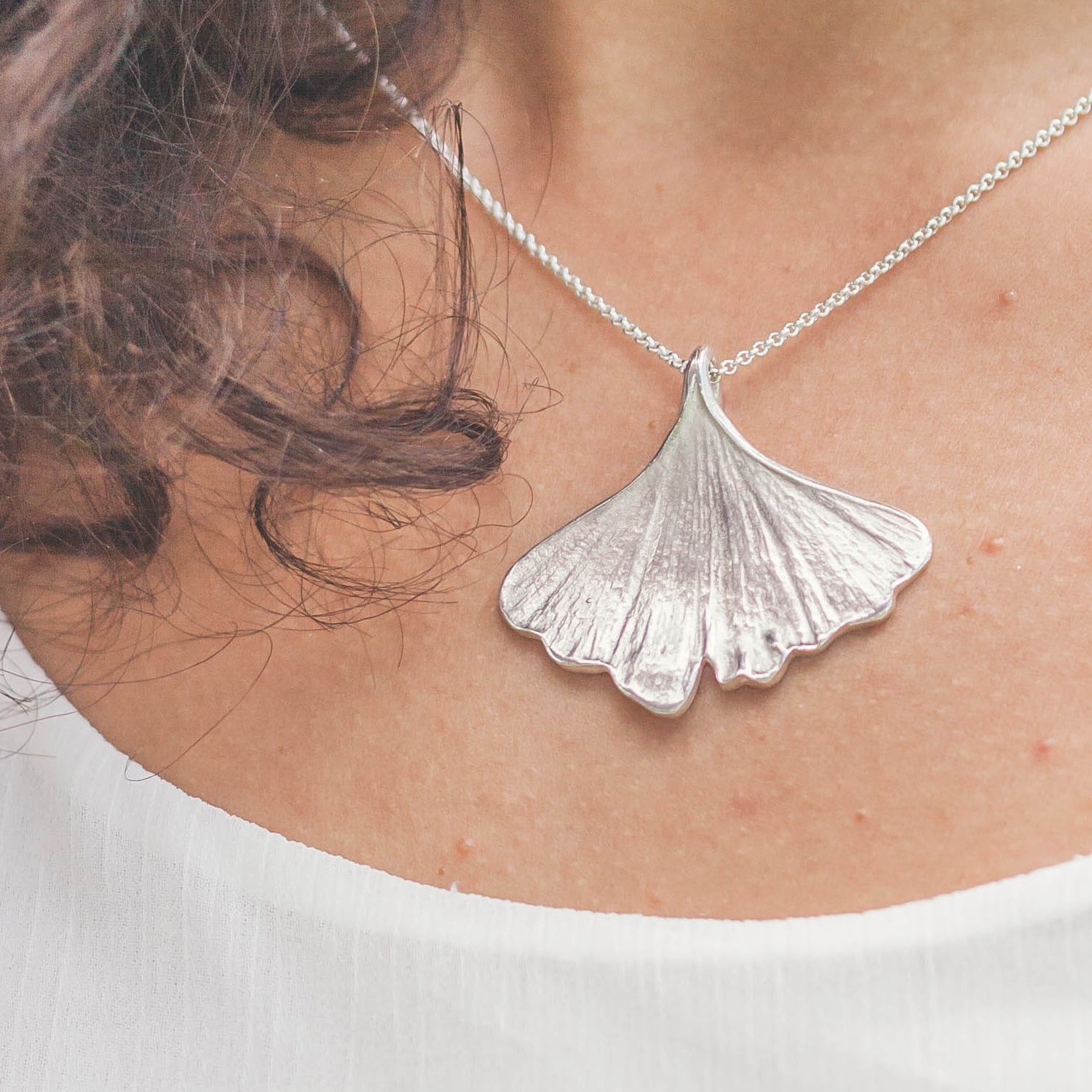 sterling silver ginkgo necklace worn with white shirt